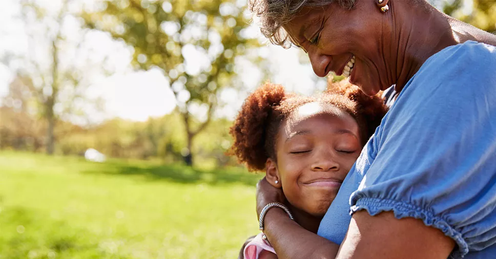 mulher abraçando a neta em um jardim represente os avós pagam a pensão alimentícia dos netos